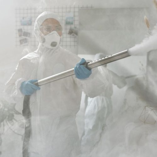 A person in full protective gear fumigating a room to ensure sterilization against viruses.